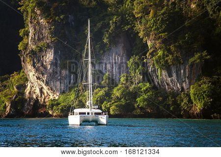 The yacht on the background of rocks. A huge mountain in the background