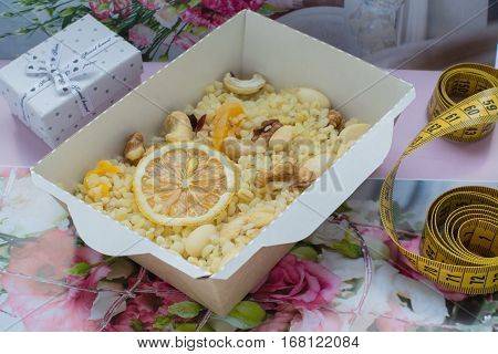 bulgur with nuts decorated with the dihydrogenated lemon in a craft box. The word loving and a box with a gift on a flower background. Healthy nutrition dish.
