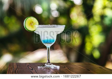 Margarita Cocktail with ice on the background of the tropics. A cold drink in the tropics