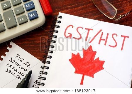 GST / HST written in a note on a wooden surface.