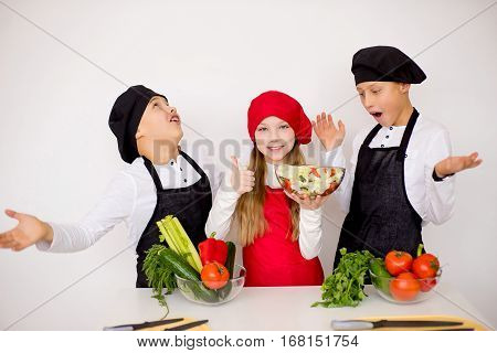 three young chefs near the white table evaluate a salad isolated. godlike