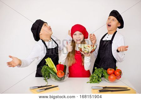 three young chefs near the white table evaluate a salad isolated. godlike