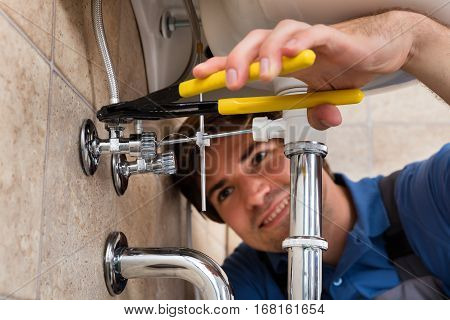 Close-up Of Male Plumber Installing Kitchen Sink Using Wrench