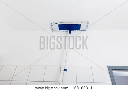 Low Angle View Of Mop Wiping On The Ceiling Of The Bathroom