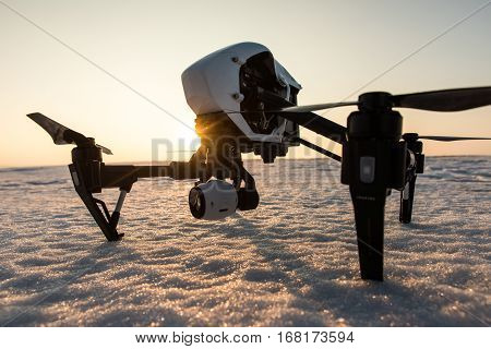 White drone with digital camera standing on snow in winter.