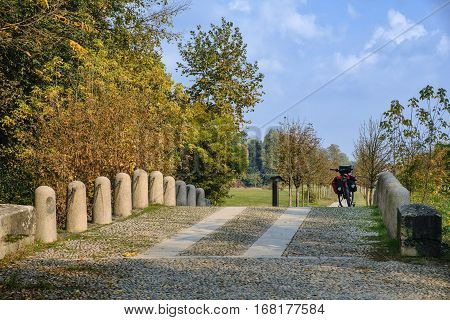 Monza (Brianza Lombardy Italy): the park at fall (october) a bicycle with bags on a stone bridge over the Lambro river