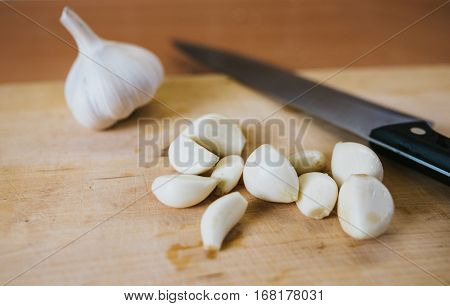 Fresh pealed garlic on wooden cutting board for food. Knife and ingrediet background.