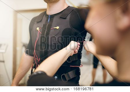 Woman Helping Man With Putting Ems Suit On