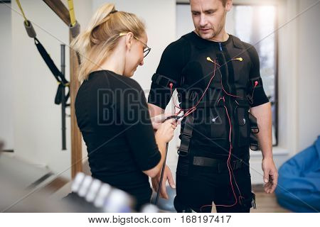 Female Trainer Connecting Cables On Sportsman Ems Suit