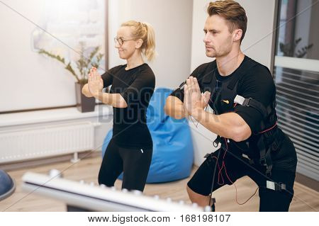 Sportsman In Ems Suit And His Personal Trainer In Yoga Pose