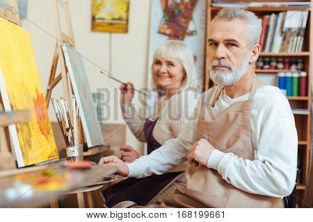 Perfect cooperation. Smiling talented concentrated colleagues drawing a picture while spending time in painting class and working as artists.
