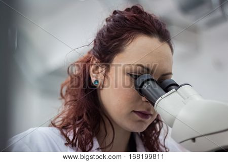 A Female Medical Or Scientific Researcher Or Woman Doctor Looking Through A Microscope In A Laborato
