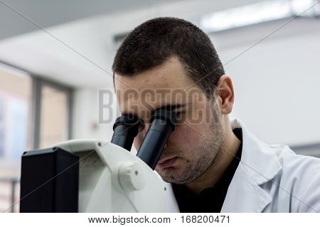 Female Medical Or Scientific Researcher Man Doctor Looking Through A Microscope In A Laboratory. You