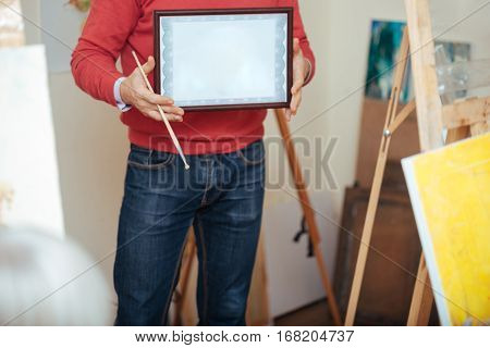 Finally graduated. Close up of young handsome man demonstrating a painters diploma being given to him after finishing painting school.