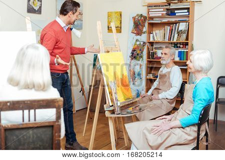 Something to say. Handsome talented young artist lecturing while working and spending time in painting school.