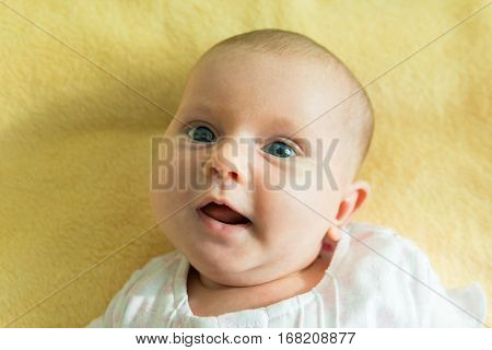 Portrait On An Adorable Innocent Child On Yellow Blanket