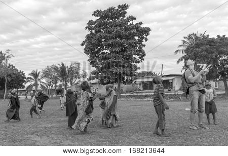 ZANZIBAR, TANZANIYA- JULY 16: european man launching quadrocopter among african childrenon July 16, 2016 in Zanzibar. black and white photo