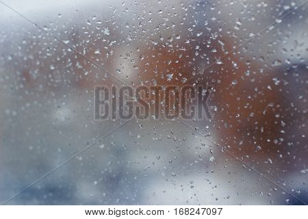 city landscape is hardly distinguishable through a muddy window with rain drops, orange structure