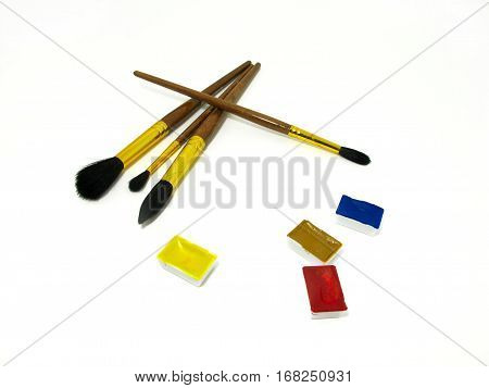 Brushes and watercolor couvettes on white background in a chaotic manner.