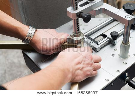 Craftsman working on frame in frameshop. Professional framer hand holding frame angle. Top view.