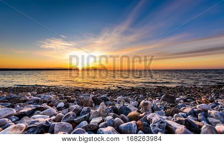 Stones On A Beach With Sunset On The Ocean Sea.