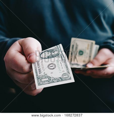 Man giving one us dollar banknote and holding cash in hands. Money credit concept.
