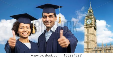 education, graduation, gesture and people concept - happy international students in mortar boards and bachelor gowns showing thumbs up over big ben clock tower in london city background