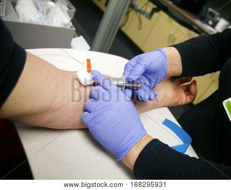 An unidentifiable person gets their blood drawn by a phlebotomist or doctor or nurse at a doctors office. Healthcare and Medical images 