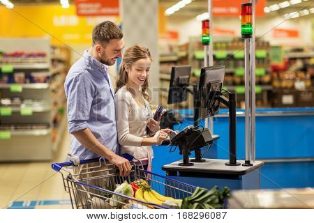 shopping, sale, consumerism and people concept - happy couple buying food at grocery store or supermarket self-service cash register