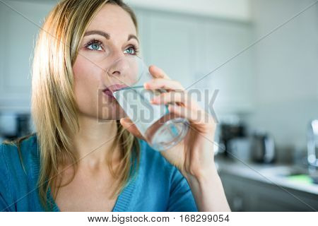 Pretty blonde woman drinking a glass of water at home