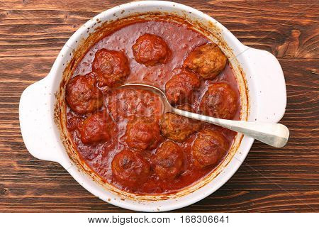 Meatballs with tomato sauce on wooden background