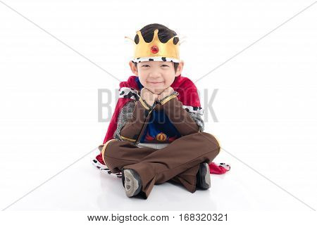Little Asian boy prince with crown sitting on white background isolated