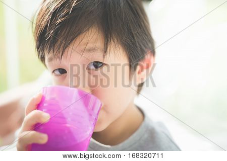 Cute Asian child drinking water in the glassCute Asian child drinking water in the glass
