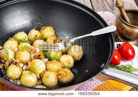 Fried potato dumplings with bacon in frying pan. Studio Photo