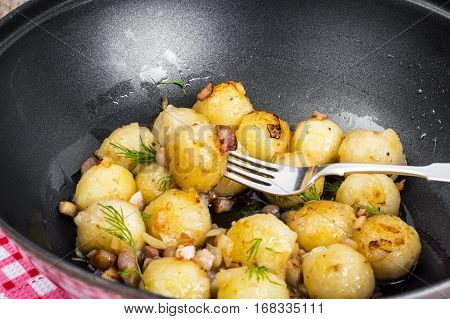 Fried potato dumplings with bacon in frying pan. Studio Photo