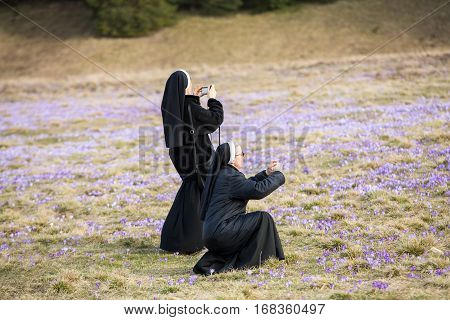 CHOCHOLOWSKA VALLEY, POLAND - MARCH 31, 2016: Nuns on mountain meadow with crocus flowers blooming