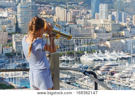 Girl looks through binoculars at observation from observation deck of palace Grimaldi