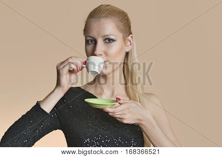 Portrait of beautiful young woman drinking tea over colored background