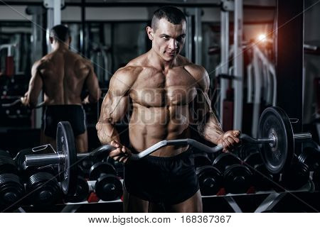 Athlete muscular bodybuilder in the gym training with bar