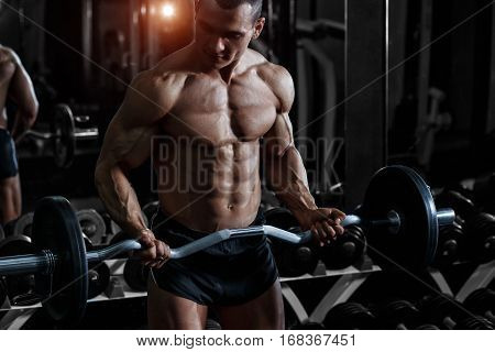 Athlete muscular bodybuilder in the gym training with bar