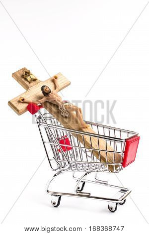 Crucifix in shopping cart. Conceptual representation of commodification of religion loss of faith blasphemy.