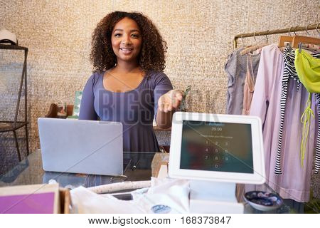 Assistant at clothing store shows computer used for payment