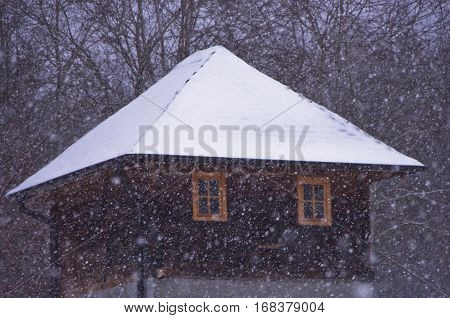 Vintage house with roof covered with snow during snow storm, mountain Kozomor, Serbia