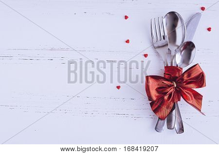 Valentine's Day tabble setting with cutlery on white shabby chic background. Valentine's Day place setting cutlery on white wooden background. Romantic love Valentines concept. Copy space. Top view.