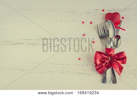 Valentine's Day tabble setting with cutlery on white shabby chic background. Valentine's Day place setting cutlery on white wooden background. Romantic love Valentines concept. Copy space. Top view.