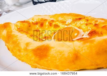 Ajarian khachapuri with yolk on white plate