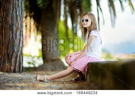 Cute Little Girl Wearing Sunglasses On A Shore Of Lake Garda In Toscolano-maderno, A Small Town And