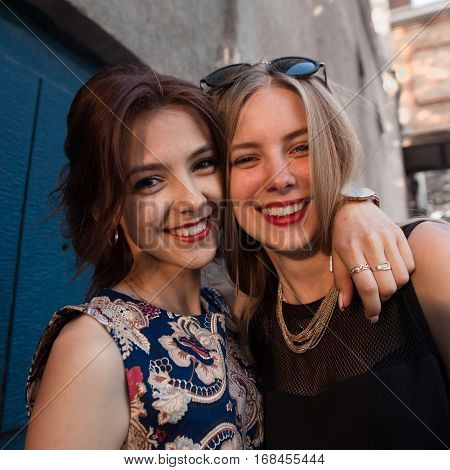Two beautiful girl hugging each other,looking at camera.Closeup photo of strong true friendship of beautiful girls.Outdoor lifestyle portrait of two best friends,having fun together, joy and happiness
