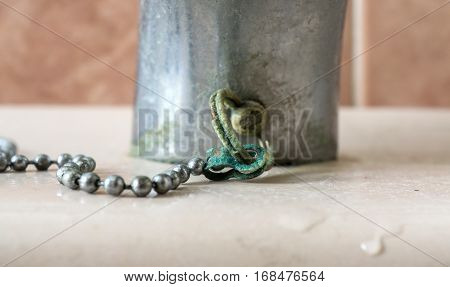 Calcium deposits on balls chain bathroom sink stopper on detail. Limescale problems