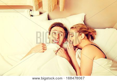 Woman whispering to her husband and he laughting